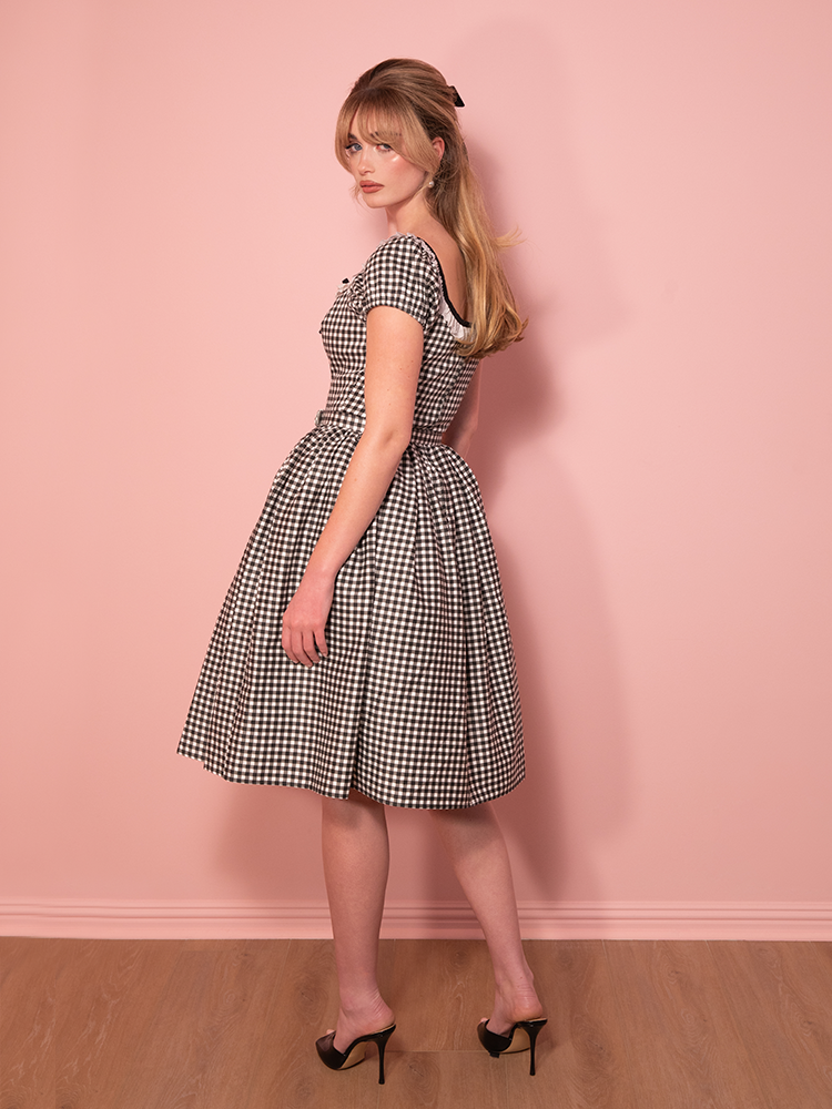 Retro elegance in every stitch, this Bardot swing dress in black gingham hugs the waist and flares into a twirl-worthy shape that exudes timeless style.
