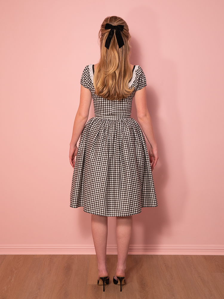 A must-have for any vintage wardrobe, this black gingham swing dress blends classic pin-up charm with a sophisticated off-the-shoulder touch.
