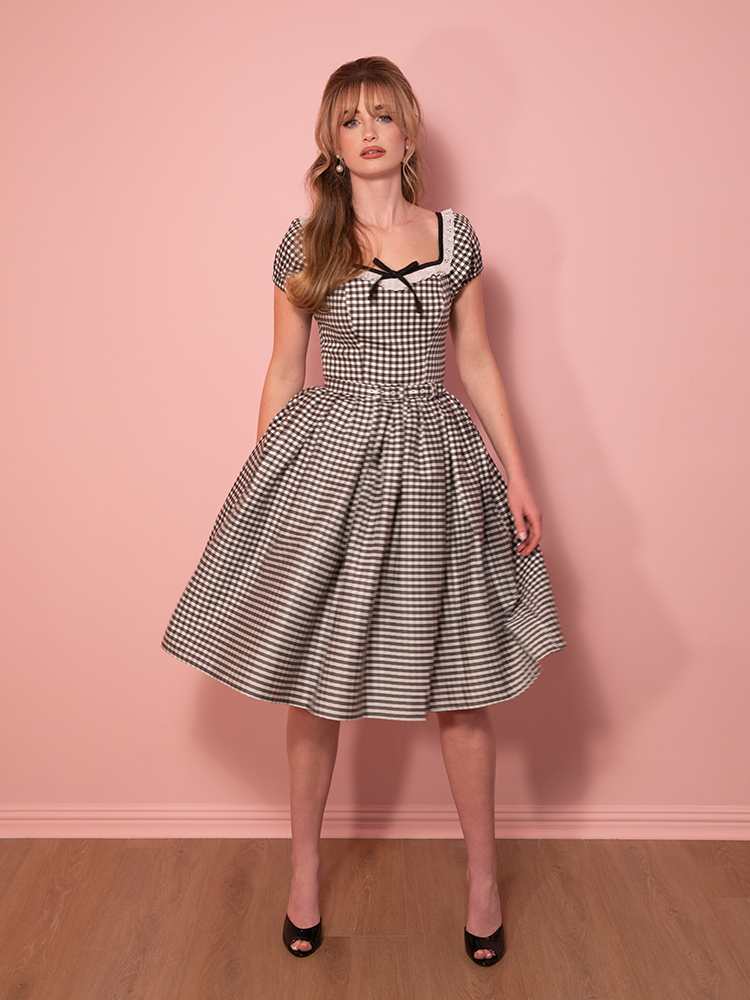 The ultimate vintage-inspired dress, this black gingham beauty stuns with an elegant Bardot neckline and a breezy full skirt for effortless charm.
