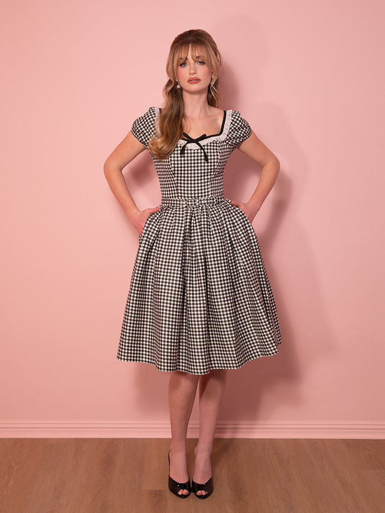 Flattering and feminine, this Bardot swing dress in black gingham highlights the shoulders while offering a classic fit-and-flare design.
