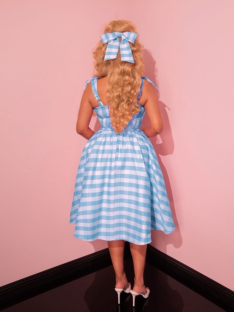 The Dream-House Swing Dress in Baby Blue Gingham is pure vintage magic, with its soft checkered print, structured yet flowing design, and a matching bow that ties the whole look together beautifully.