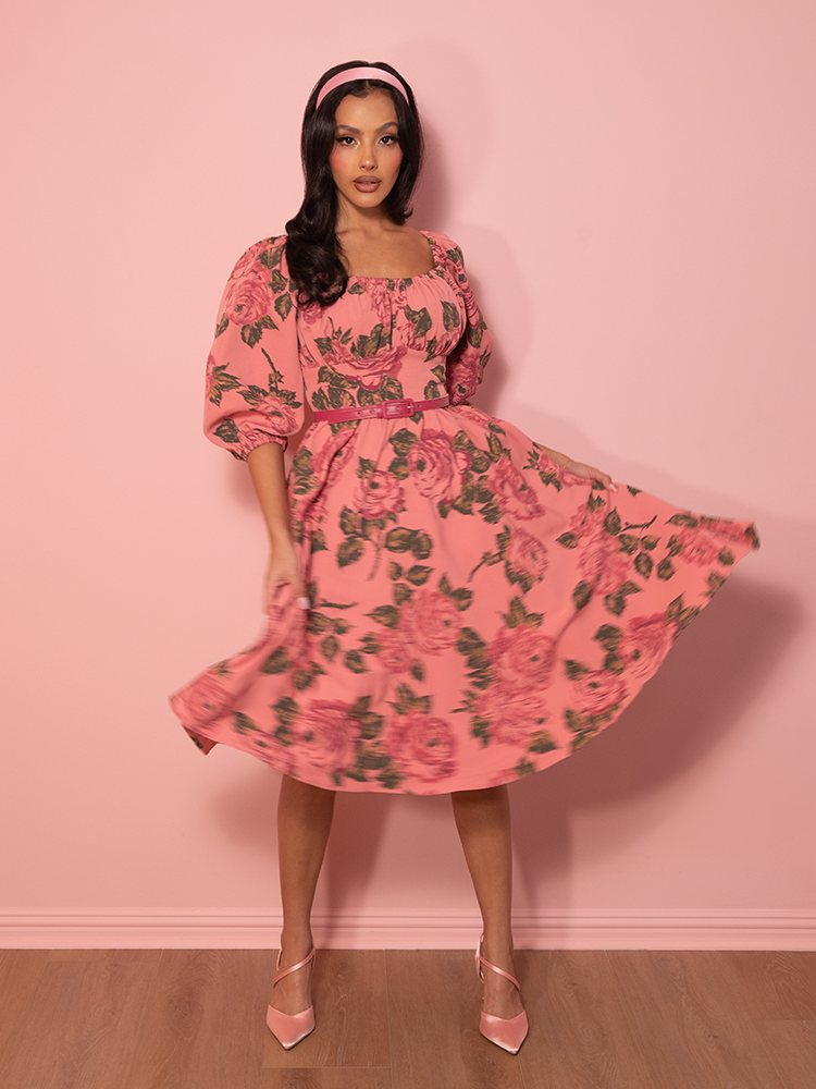 A vacation wardrobe essential, this vintage-inspired dress in blush pink roses brings soft, romantic charm to any getaway or special occasion.
