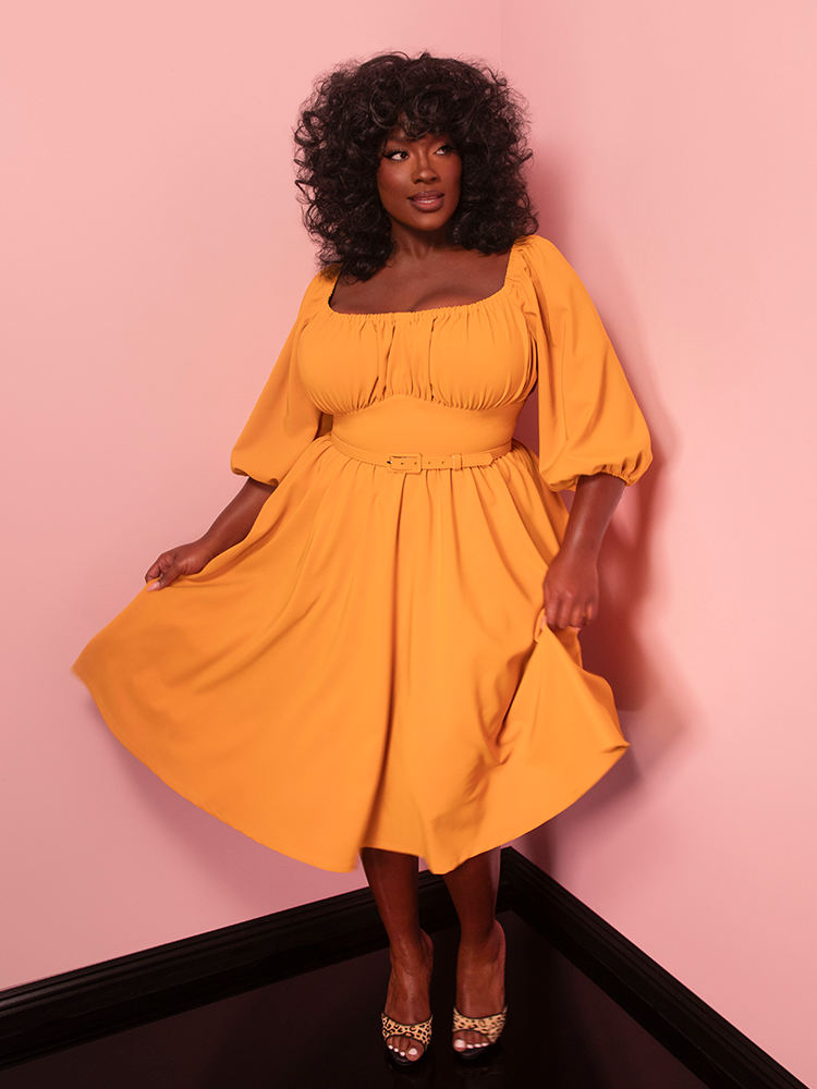 The Vacation Dress in Mustard Gold is a sunny tribute to vintage glamour. Perfect for a stroll on the beach or a weekend picnic, it exudes effortless charm.