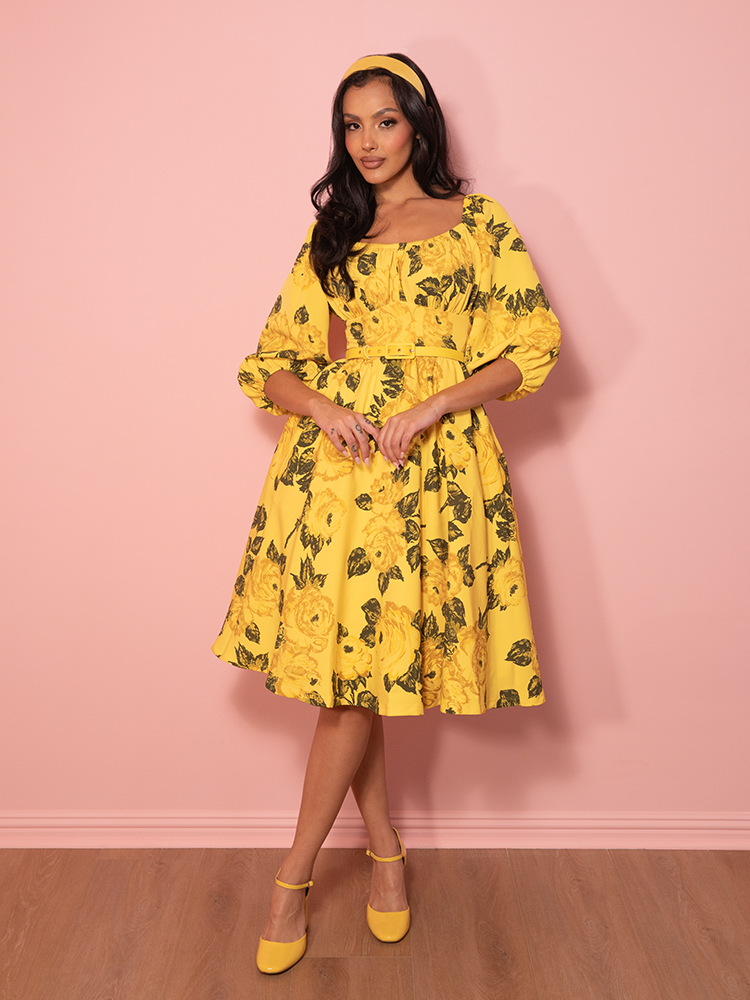 Bright, cheerful, and timelessly elegant, this vintage-inspired vacation dress blooms with delicate yellow roses for the perfect romantic getaway look.
