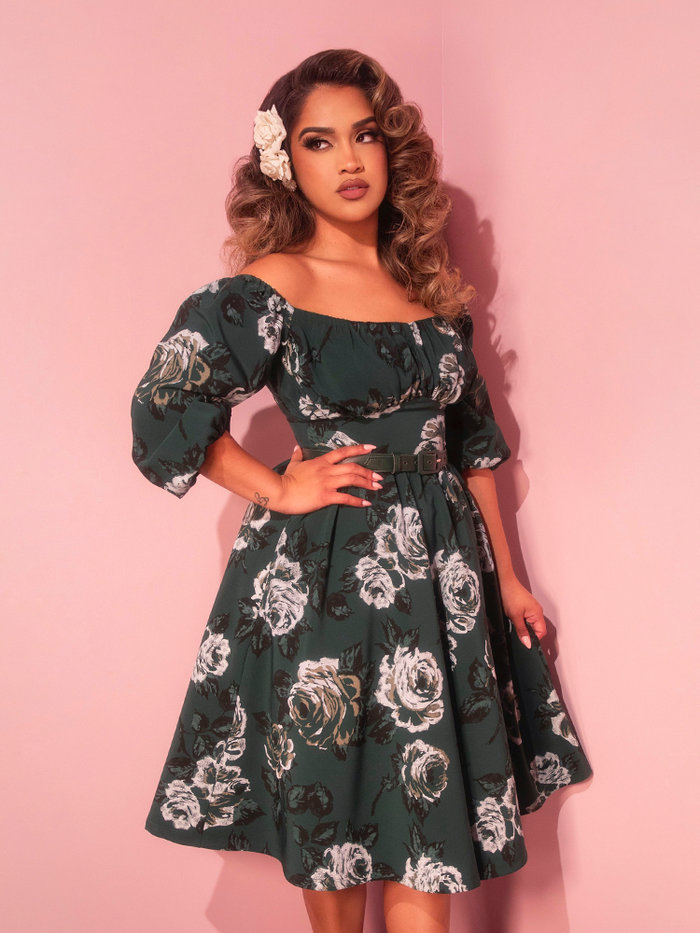 Embrace timeless elegance with this vacation-ready vintage dress adorned in green roses, perfect for strolls along charming cobblestone streets. Its classic design exudes effortless sophistication inspired by the golden age of Hollywood.