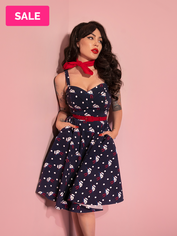 Micheline Pitt with her hands tucked into the pockets of her GHOSTBUSTERS™ Maneater Swing Dress in Stay Puft Novelty Print from retro dress company Vixen Clothing.