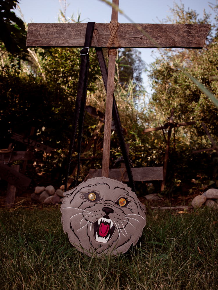 Pet Sematary Church the Cat Cross Body Bag pictured with strap hanging from makeshift cross in graveyard.