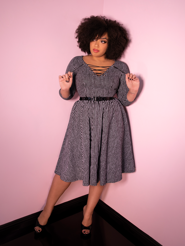 A full length shot of Ashleeta looking off camera while modeling the Miss Kitty swing dress in black stripes.