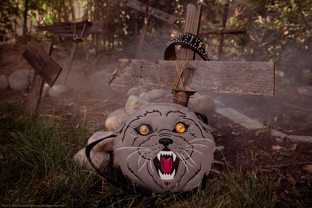 Close-up shot of Pet Sematary cat novely bag placed against two pieces of old wood made into a makeshift cross.